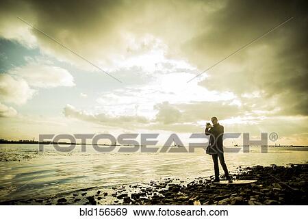 Caucasian tourist photographing rocky beach View Large Photo Image Stock Photo - Caucasian tourist photographing rocky beach. Fotosearch