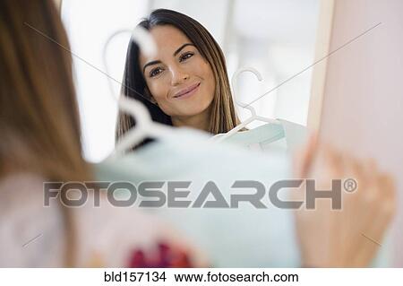 Picture - Caucasian woman admiring shirt in mirror. Fotosearch