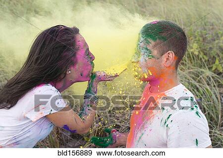 Stock Photo - Caucasian woman blowing paint powder on boyfriend. Fotosearch