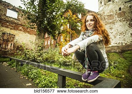 Stock Photo - Caucasian woman crouching on wooden banister. Fotosearch