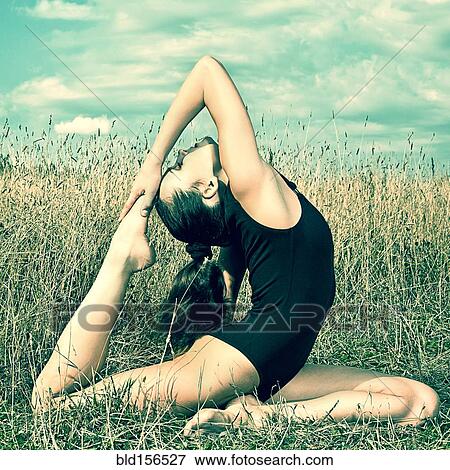 Stock Photo - Caucasian woman doing backbend in tall grass. Fotosearch