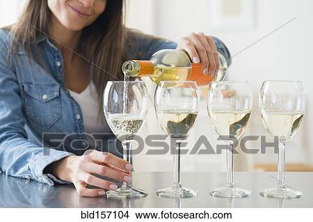 Picture - Caucasian woman pouring glasses of white wine. Fotosearch