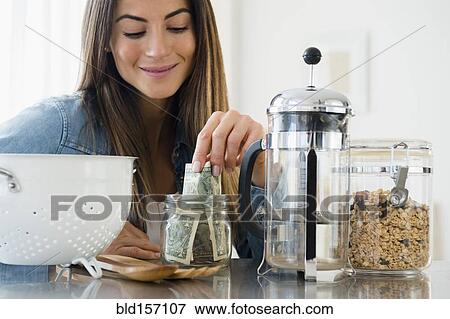 Caucasian woman putting money in jar View Large Photo Image Stock Photo - Caucasian woman putting money in jar. Fotosearch