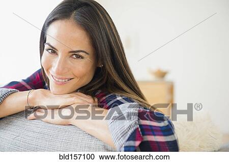 Stock Image - Caucasian woman smiling on sofa. Fotosearch