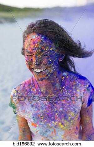 Stock Image - Caucasian woman splattered with paint powder with eyes closed. Fotosearch