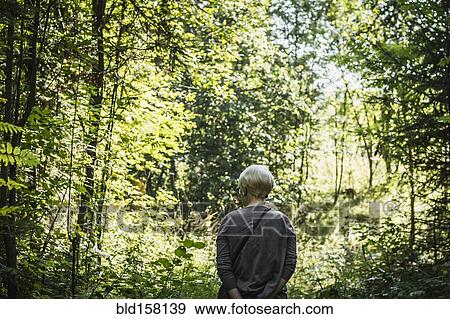 Stock Photo - Caucasian woman standing in forest. Fotosearch