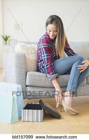 Stock Photo - Caucasian woman trying on high heels on sofa. Fotosearch