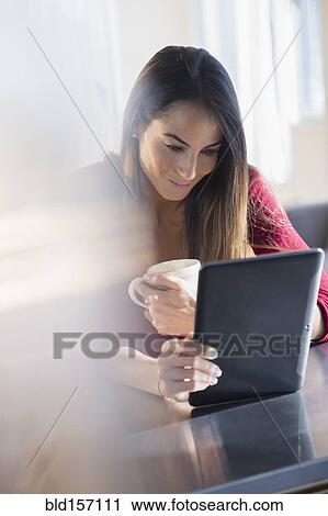 Stock Image - Caucasian woman using digital tablet with coffee. Fotosearch