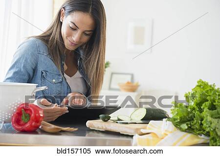 Stock Photography - Caucasian woman using digital tablet for recipe. Fotosearch