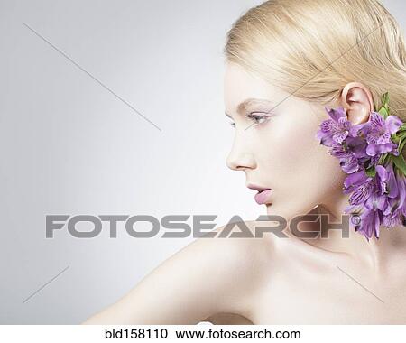 Stock Image - Caucasian woman wearing purple flowers in hair. Fotosearch