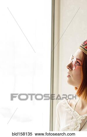 Stock Photography - Caucasian woman wearing sunglasses near window. Fotosearch