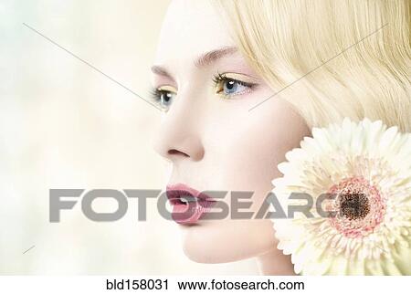 Stock Image - Caucasian woman with pink lipstick wearing white flower. Fotosearch