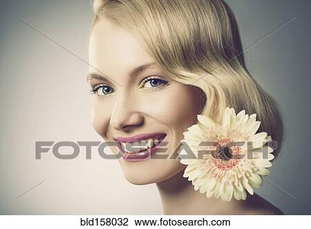 Stock Image - Caucasian woman with pink lipstick wearing white flower. Fotosearch