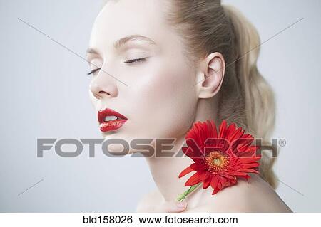 Caucasian woman with red lipstick holding matching flower View Large Photo Image Stock Photograph - Caucasian woman with red lipstick holding matching flower. Fotosearch