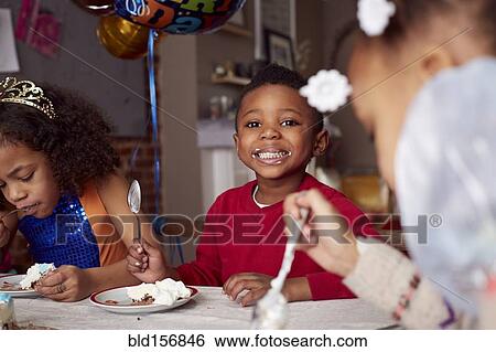 Stock Photograph - Children eating cake at party. Fotosearch