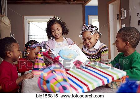 Stock Photography - Children wearing tiaras and opening gifts. Fotosearch