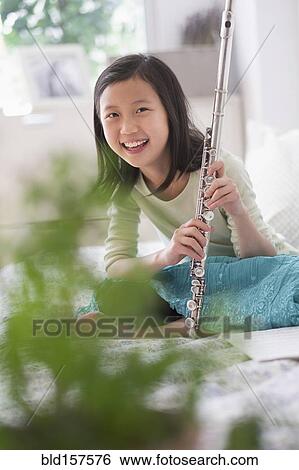 Stock Photograph - Chinese girl holding flute on bed. Fotosearch