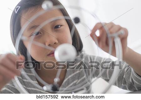 Stock Image - Chinese student examining molecular model. Fotosearch