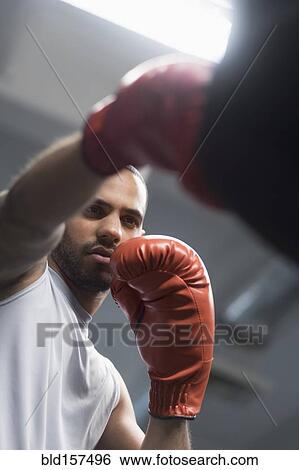 Close up of Hispanic man punching bag in gym View Large Photo Image Stock Photograph - Close up of Hispanic man punching bag in gym. Fotosearch