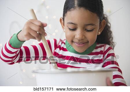 Stock Image - Close up of mixed race girl stirring dough. Fotosearch