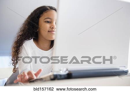 Stock Image - Close up of mixed race girl using laptop. Fotosearch