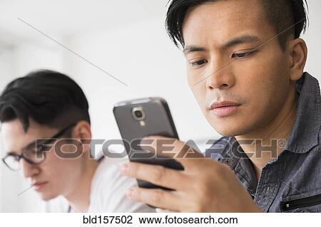 Stock Image - Close up of serious man texting on cell phone. Fotosearch