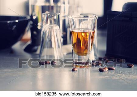 Stock Photography - Close up of shot glass with coffee beans on table. Fotosearch