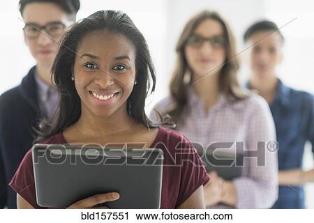 Stock Image - Close up of smiling businesswoman holding digital tablet in office. Fotosearch