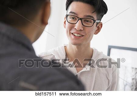 Stock Image - Close up of smiling men talking. Fotosearch
