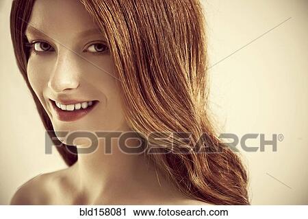 Stock Image - Close up of smiling woman with long red hair. Fotosearch