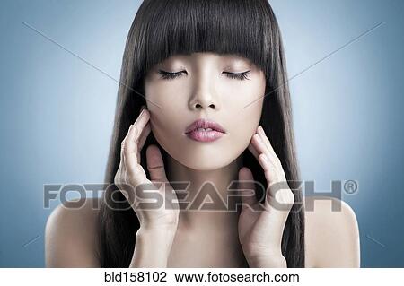 Stock Image - Close up of tranquil woman rubbing her face. Fotosearch
