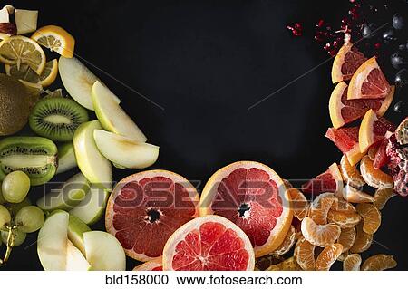 Stock Image - Close up of variety of sliced fruit. Fotosearch