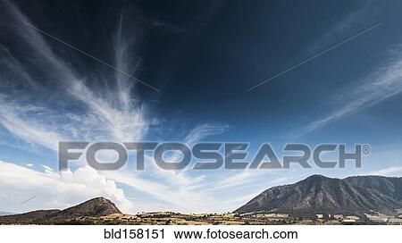 Stock Image - Cloudy blue sky over mountains in remote landscape. Fotosearch