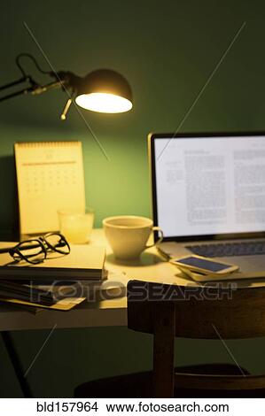 Computer and cell phone illuminated by desk lamp at night View Large Photo Image Picture - Computer and cell phone illuminated by desk lamp at night. Fotosearch