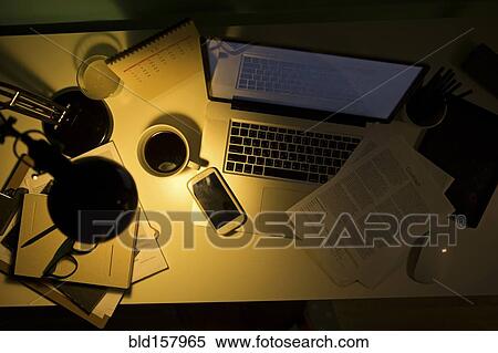 Stock Photography - Computer and cell phone illuminated by desk lamp at night. Fotosearch