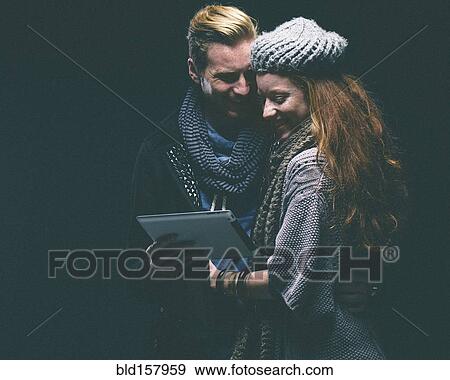 Stock Photo - Couple wearing warm clothing using digital tablet. Fotosearch