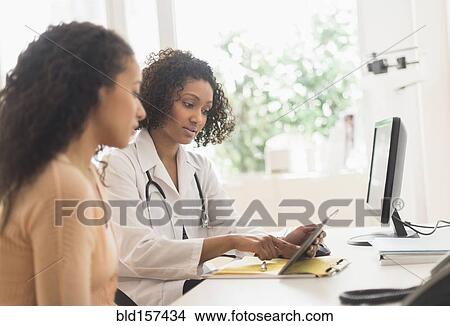 Picture - Doctor and patient using digital tablet in office. Fotosearch