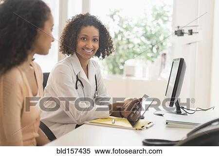 Stock Photography - Doctor and patient using digital tablet in office. Fotosearch