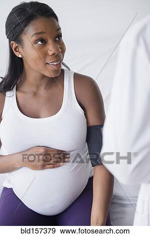 Doctor checking blood pressure of Black pregnant woman View Large Photo Image Stock Photo - Doctor checking blood pressure of Black pregnant woman. Fotosearch
