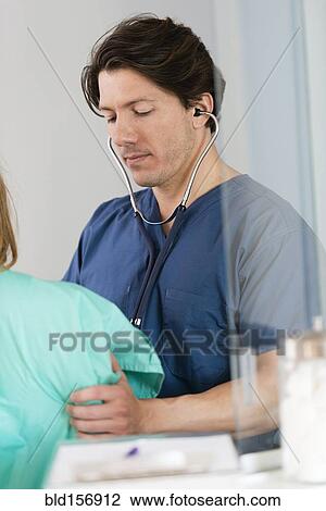 Stock Image - Doctor listening to heartbeat of patient. Fotosearch