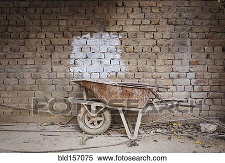 Empty wheelbarrow near brick wall View Large Photo Image Stock Photography - Empty wheelbarrow near brick wall. Fotosearch