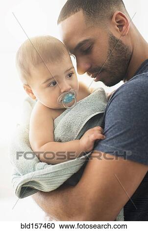 Stock Image - Father drying baby son with towel after bath. Fotosearch