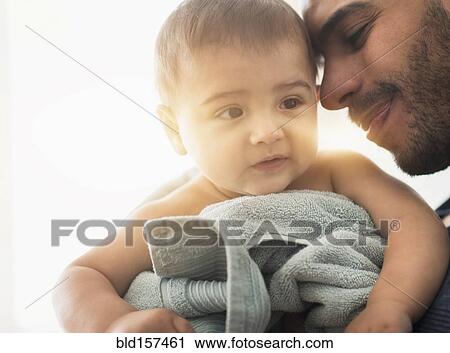 Stock Image - Father drying baby son with towel after bath. Fotosearch