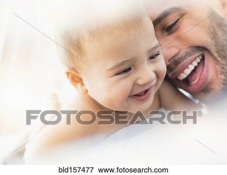 Stock Photo - Father holding baby son in towel after bath. Fotosearch