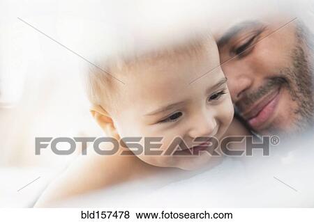 Stock Photo - Father holding baby son in towel after bath. Fotosearch