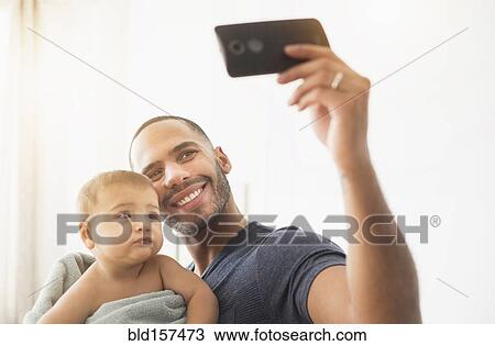 Father taking cell phone photograph with baby son View Large Photo Image Stock Image - Father taking cell phone photograph with baby son. Fotosearch
