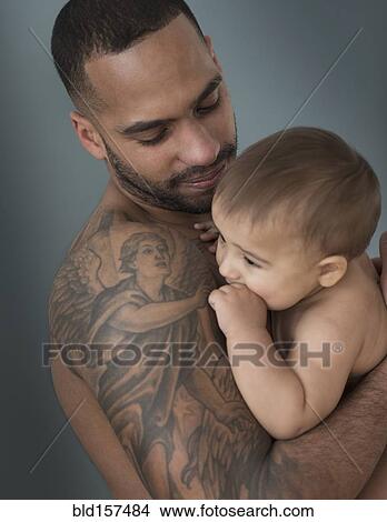 Father with tattoos holding baby son View Large Photo Image Picture - Father with tattoos holding baby son. Fotosearch