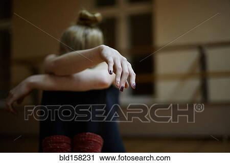 Stock Image - Fatigued Caucasian dancer sitting on studio floor. Fotosearch