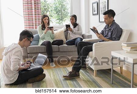 Picture - Friends using technology in living room. Fotosearch