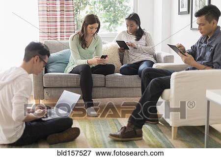 Friends using technology in living room View Large Photo Image Stock Photo - Friends using technology in living room. Fotosearch